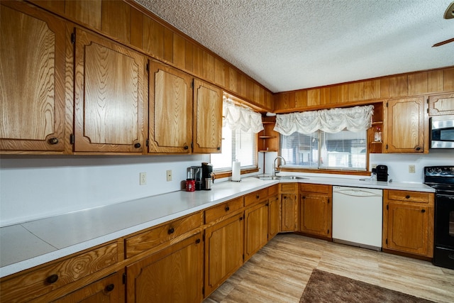 kitchen with a textured ceiling, dishwasher, sink, black range with electric stovetop, and light hardwood / wood-style flooring