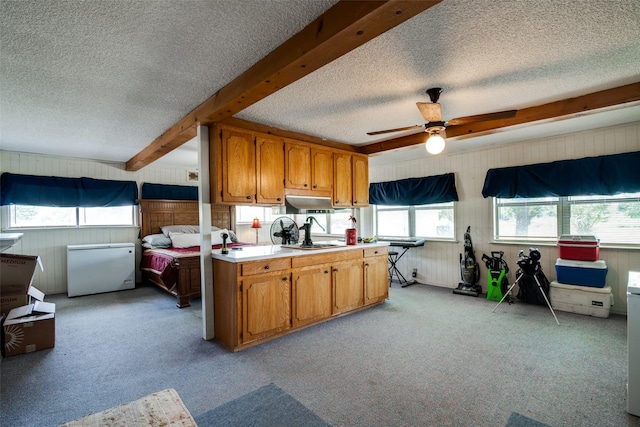 kitchen featuring ceiling fan, beam ceiling, and light carpet