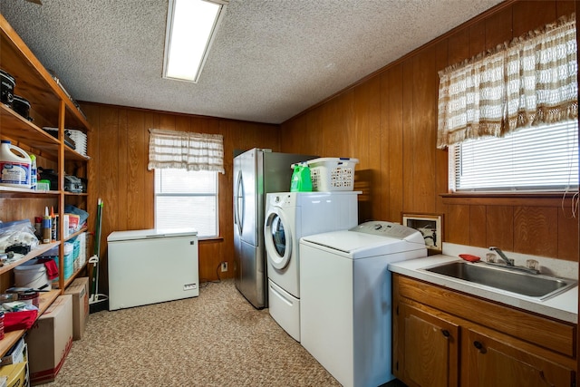 laundry room featuring sink, wooden walls, and washing machine and dryer