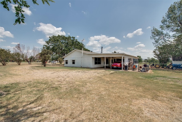 rear view of house featuring a lawn and a carport