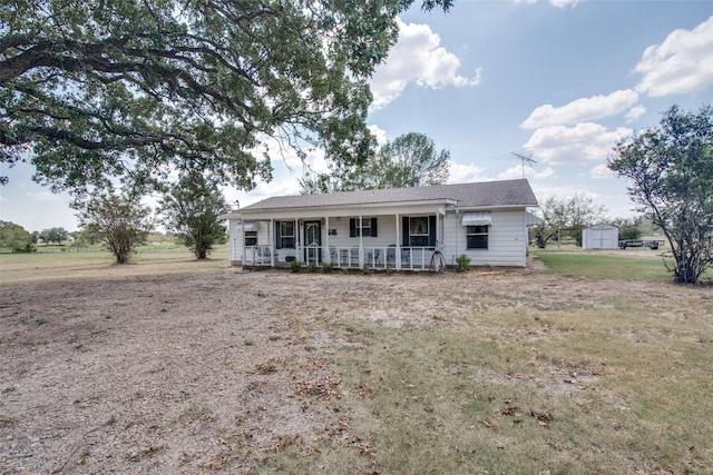 ranch-style home featuring covered porch, a front yard, and a shed