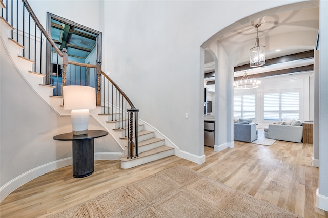 entrance foyer featuring beamed ceiling, hardwood / wood-style floors, and an inviting chandelier