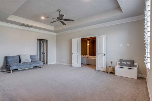 sitting room with a raised ceiling, ceiling fan, ornamental molding, and light colored carpet