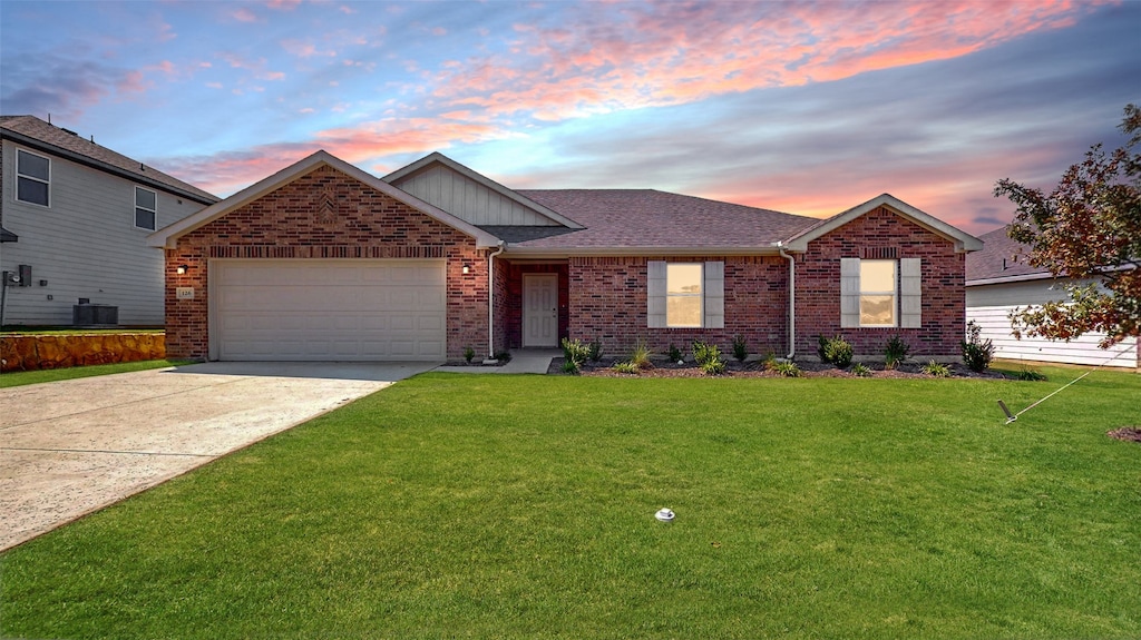 view of front facade with a garage, a lawn, and central AC unit