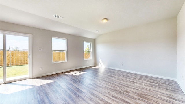 unfurnished room featuring lofted ceiling and light hardwood / wood-style floors