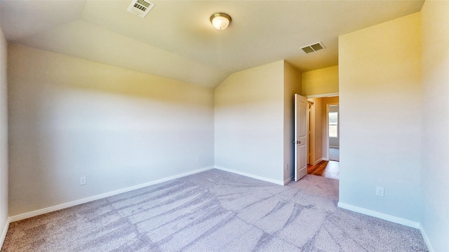 carpeted spare room with lofted ceiling