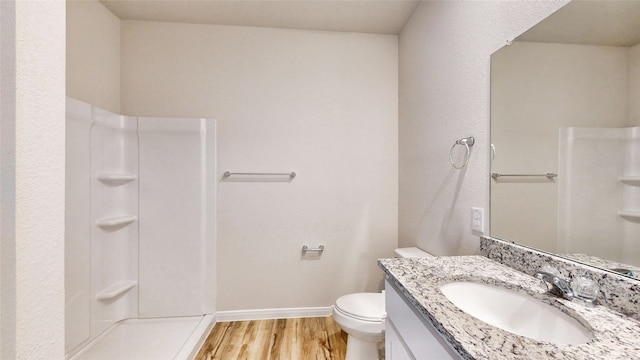 bathroom featuring hardwood / wood-style floors, vanity, toilet, and a shower