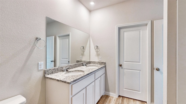 bathroom with hardwood / wood-style flooring, toilet, and vanity