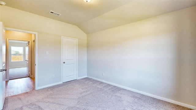 unfurnished bedroom with light carpet, lofted ceiling, and a closet