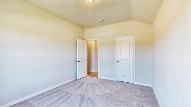 unfurnished bedroom featuring lofted ceiling and light colored carpet