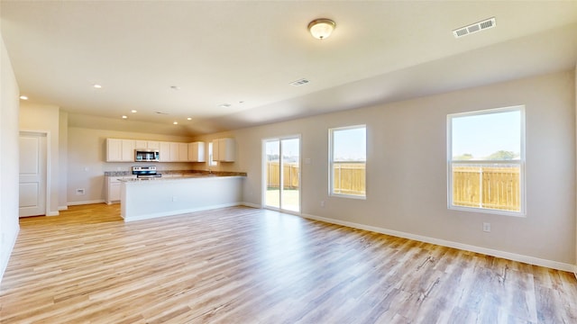 unfurnished living room featuring plenty of natural light and light hardwood / wood-style floors