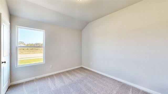 carpeted empty room featuring vaulted ceiling