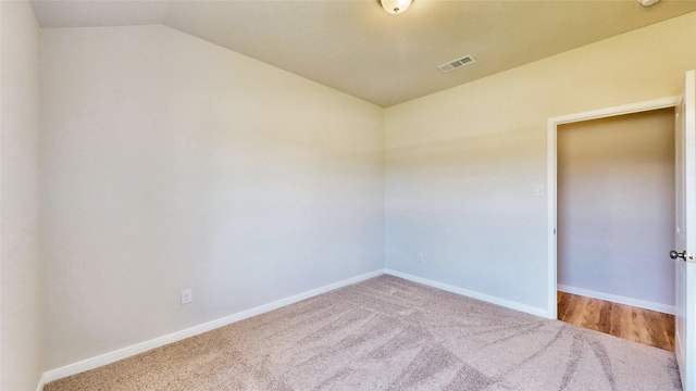 empty room featuring light colored carpet and lofted ceiling