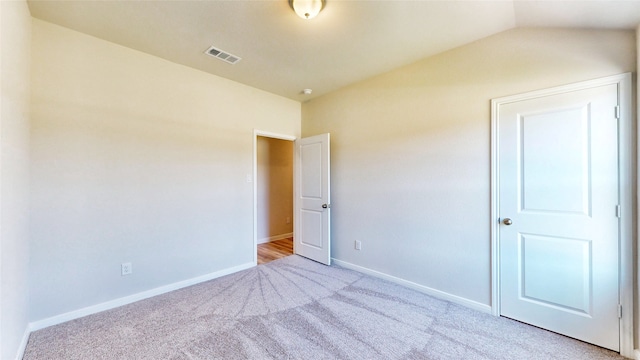 unfurnished bedroom featuring light carpet and vaulted ceiling