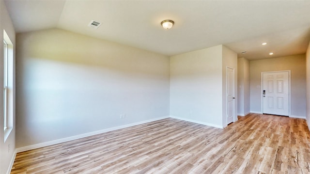 unfurnished room with vaulted ceiling and light hardwood / wood-style flooring