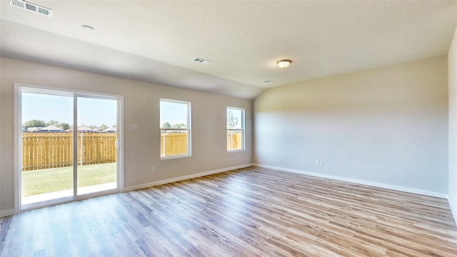 empty room featuring vaulted ceiling and light hardwood / wood-style flooring