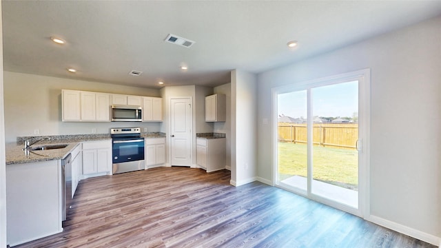 kitchen featuring white cabinets, stainless steel appliances, light wood-type flooring, and sink