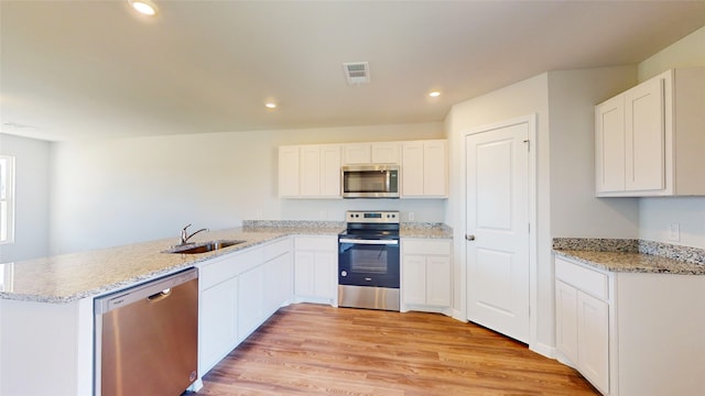 kitchen featuring stainless steel appliances, sink, light hardwood / wood-style floors, kitchen peninsula, and white cabinetry