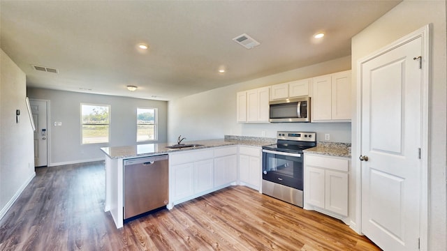 kitchen featuring light hardwood / wood-style flooring, sink, stainless steel appliances, kitchen peninsula, and white cabinetry