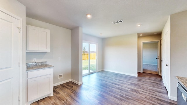 kitchen with light stone counters, stainless steel dishwasher, dark hardwood / wood-style floors, white cabinets, and a textured ceiling