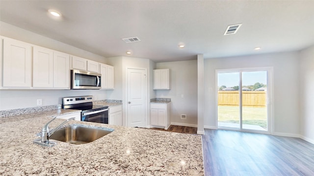 kitchen with stainless steel appliances, wood-type flooring, white cabinets, and sink