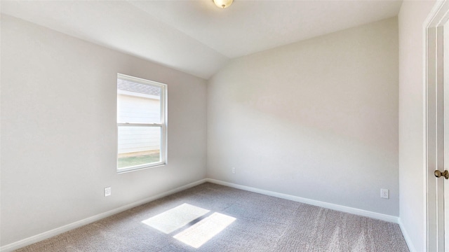 carpeted spare room with vaulted ceiling