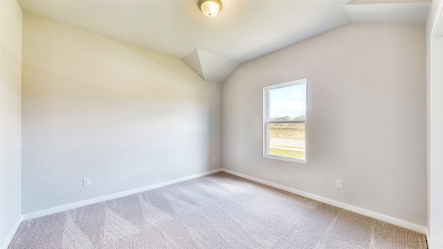 empty room with carpet floors and vaulted ceiling