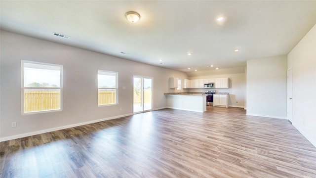 unfurnished living room featuring a wealth of natural light and light hardwood / wood-style floors