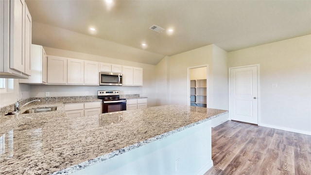 kitchen with light wood-type flooring, light stone counters, stainless steel appliances, white cabinets, and sink