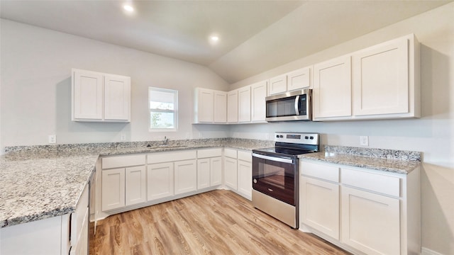 kitchen featuring light stone countertops, white cabinetry, vaulted ceiling, light hardwood / wood-style flooring, and appliances with stainless steel finishes