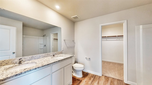 bathroom with wood-type flooring, vanity, a shower, and toilet