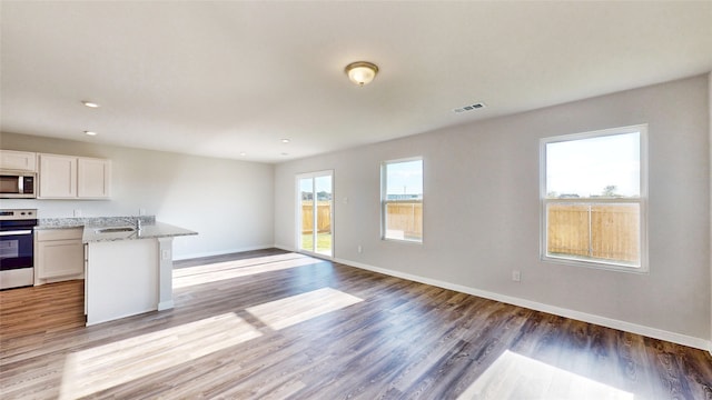 kitchen with hardwood / wood-style flooring, plenty of natural light, stainless steel appliances, and white cabinets