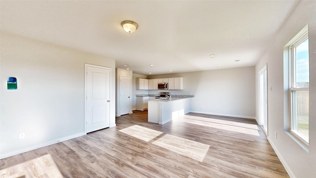 kitchen featuring kitchen peninsula, light hardwood / wood-style flooring, stainless steel appliances, and white cabinets