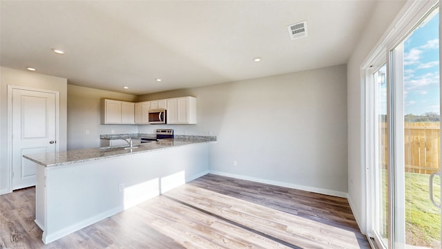 kitchen featuring white cabinets, appliances with stainless steel finishes, plenty of natural light, and kitchen peninsula