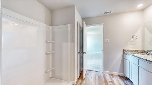 bathroom featuring walk in shower, wood-type flooring, and vanity