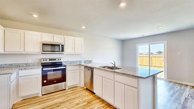 kitchen with stainless steel appliances, kitchen peninsula, sink, and white cabinetry