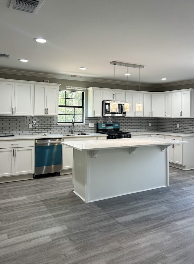 kitchen featuring hardwood / wood-style flooring, decorative backsplash, white cabinetry, and stainless steel appliances