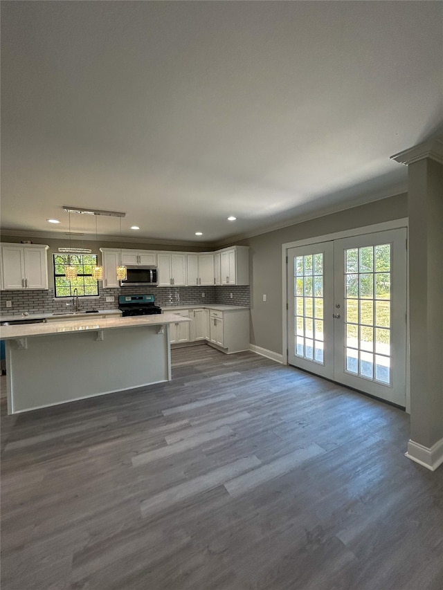 unfurnished living room featuring sink, dark wood-type flooring, a healthy amount of sunlight, and rail lighting