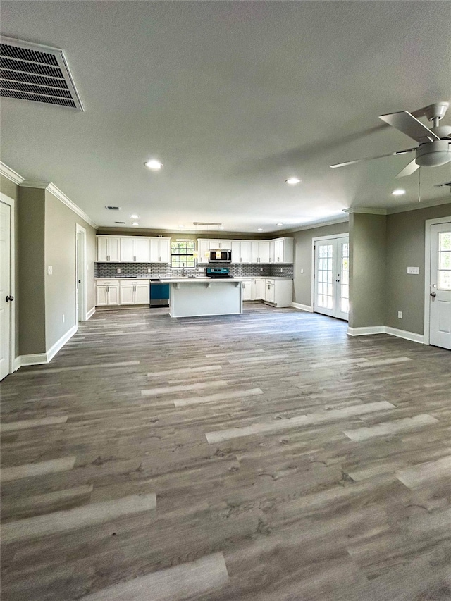 unfurnished living room featuring ceiling fan, wood-type flooring, and ornamental molding