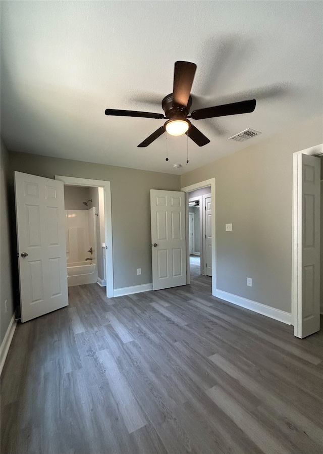 unfurnished bedroom with dark hardwood / wood-style flooring, connected bathroom, and ceiling fan