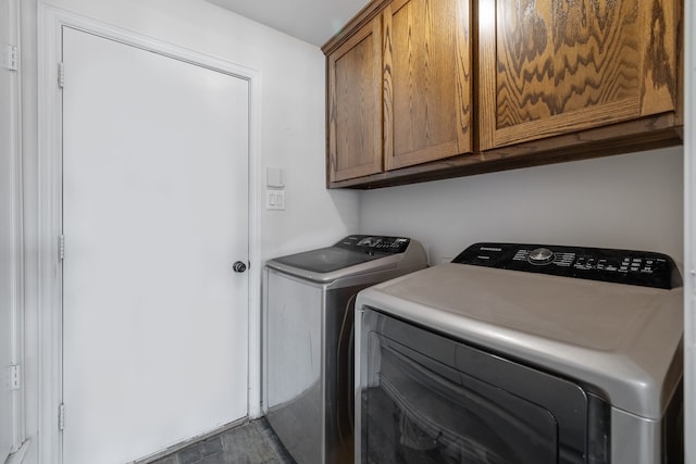 laundry area with dark tile patterned floors, washing machine and dryer, and cabinets