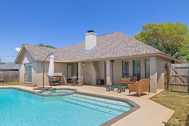 back of property featuring a patio and a pool with hot tub