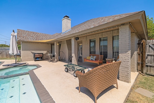 rear view of property with a patio area and a swimming pool with hot tub