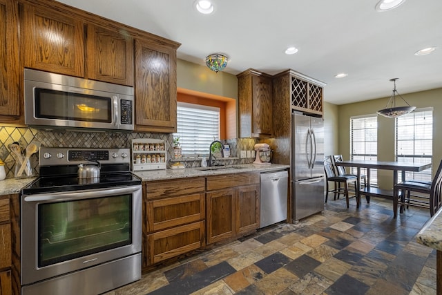 kitchen with appliances with stainless steel finishes, plenty of natural light, backsplash, and dark tile patterned floors