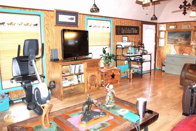 living room with wood finished floors, a ceiling fan, and wood walls