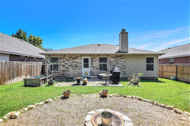 rear view of property featuring a patio area, a yard, and a fire pit