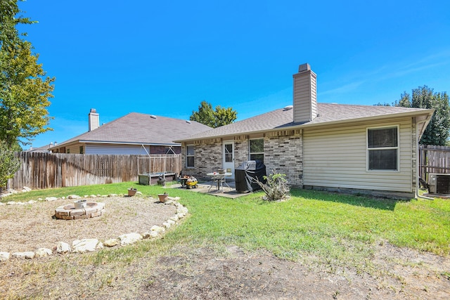 back of property with a patio, a yard, central air condition unit, and a fire pit