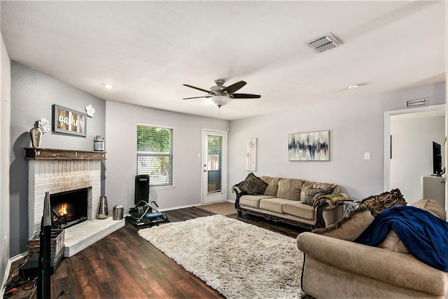 living room featuring ceiling fan, dark hardwood / wood-style flooring, and a brick fireplace