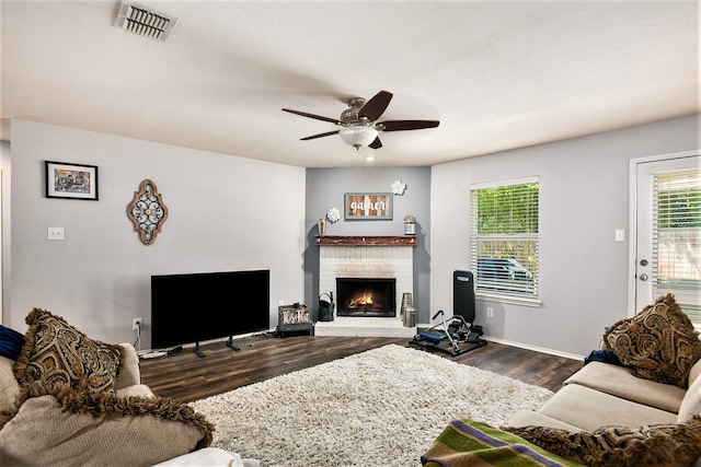 living room featuring ceiling fan, dark hardwood / wood-style floors, and a fireplace