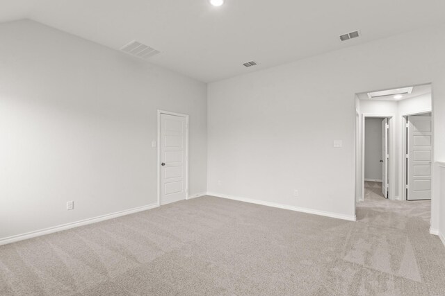 carpeted empty room featuring vaulted ceiling